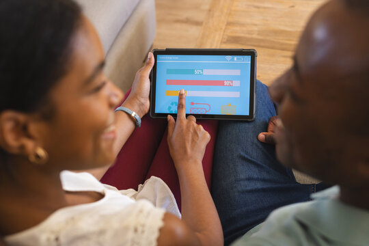 African American couple reviews finances and manages their smart home app on a tablet at home