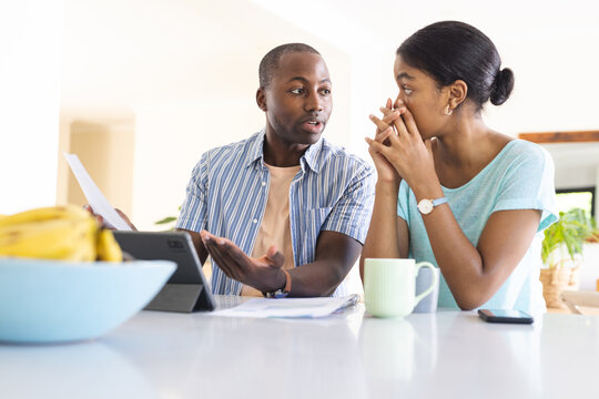 A young African American man and his partner, a biracial woman, are a couple reviewing their finance