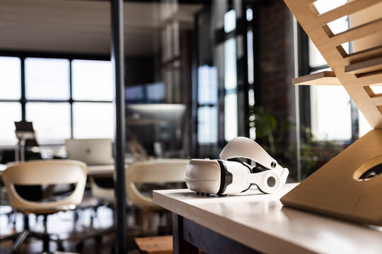 A VR headset rests on a table in a modern casual business office