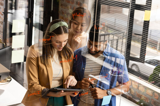 Young Caucasian woman collaborates with an Asian couple in a casual business setting in an office