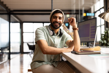 Young Asian man sits at his desk in a modern office, embodying confidence and professionalism in a c