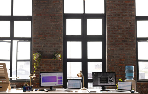 A modern casual business office setup with large windows and multiple monitors