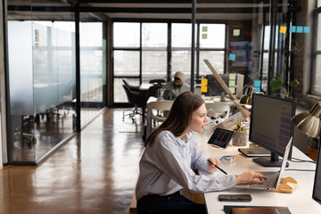 Young Caucasian woman works diligently in a modern, casual business office