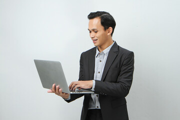 Happy asian indonesian business man in suit holding laptop computer on isolated background