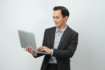 Happy asian indonesian business man in suit holding laptop computer on isolated background