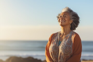 Fototapeta na wymiar An elderly happy woman stands facing the camera against the background of nature, the sea, with her arms outstretched. Relaxation and happiness in harmony with yourself