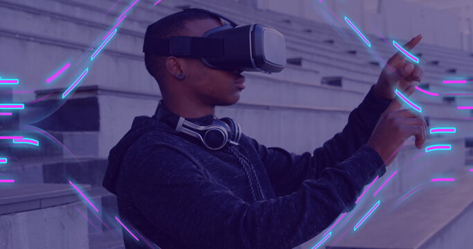Image of glowing light trails of data transfer over african american man in vr headset