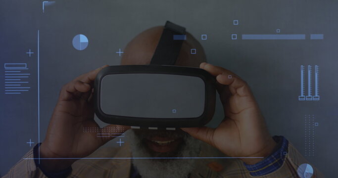 Digital interface with data processing against african american senior man removing vr headset