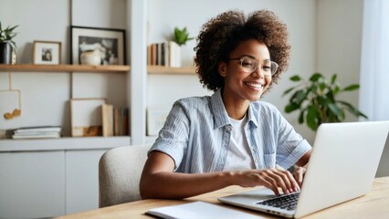 Happy African woman using laptop computer. Distance learning online education and work in white room. Smiling happy attractive African American girl working office work remotely from home.
