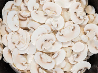 Raw sliced button mushrooms on old frying pan, top view