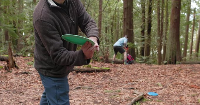 Close up shot of a man throwing a disc and hitting a tree in the Pacific Northwest forest while playing disc golf in slow motion 60 fps.