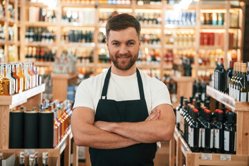 Fototapeta premium With arms crossed. Wine shop owner in white shirt and black apron