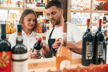 Customer service. The shop owner helps a young woman to choose a good wine