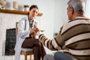 Asian caregiver nurse examine and listen to senior man patient at home. 