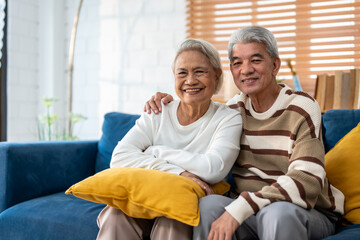 Portrait of Asian senior elderly couple sit on sofa in living room. 