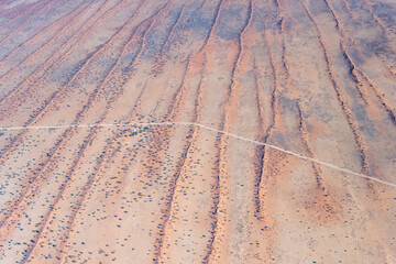 gravel road on red sand dune stripes in Kalahari, east of Kalkrand, Namibia