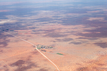 gravel road and farm with cultivated fields in desert, east of Ulenhorst, Namibia