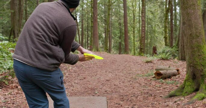Medium shot of a man throwing a disc and hitting a tree in the Pacific Northwest forest while playing disc golf in slow motion 60 fps.

