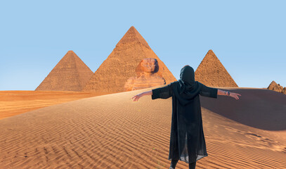 Giza Pyramid Complex at amazing sunset - Beautiful girl wearing abaya with arms up happy - Cairo,...