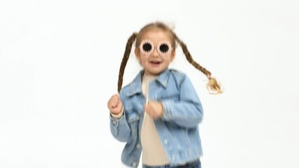 Cheerful little girl in modern clothes having fun, performing freestyle dance moves, on isolated white background. Children's clothing advertising concept