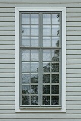 Window with many small frames with white frame on a green painted wood wall.
