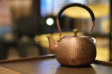 one traditional Chinese copper teapot on table with bokeh