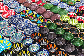 Traditional ceramics, typical handicraft uzbek souvenir. Multicolored pots and plates in Bukhara street market. Uzbekistan - obrazy, fototapety, plakaty