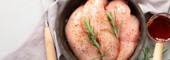 Raw marinated chicken meat with rosemary and sauce in a grey bowl. Marinating meat for cooking.