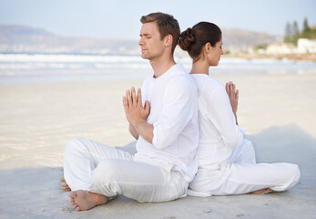 Couple, yoga and beach with meditation, peace and sitting on sand in morning with mindfulness in...