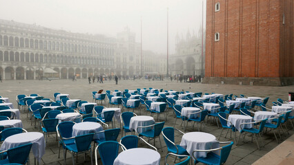 Venice in winter fog. Unused restaurant seating in Piazza San Marco, St Mark's Square with...