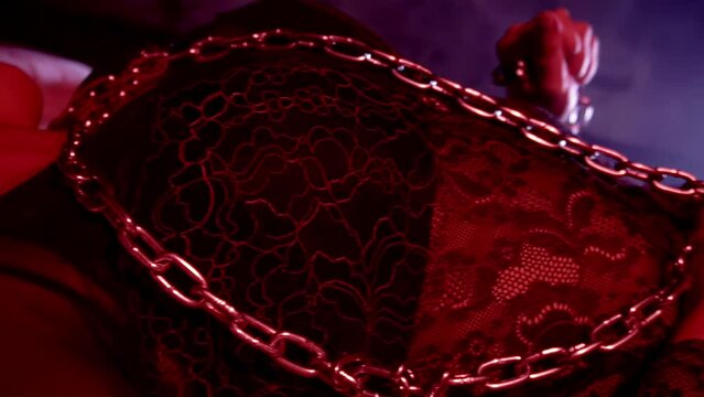 BDSM fetish. Lust. Sexual excitement arousal abstinence. Passion desire temptation. Girl bound in metal chain, she is lying in bed. Female pervert slave. Intimate adult games, punishment. Hot mistress