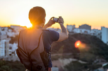 Young man taking a photo with his camera at sunset, with space for text