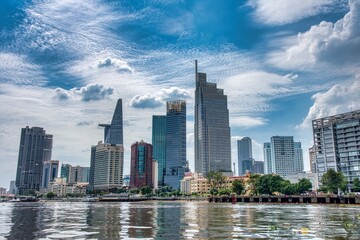 Ho Chi Minh City skyline and the Saigon River. Amazing colorful view of skyscraper and other modern buildings at downtown. Ho Chi Minh City is a popular tourist destination of Vietnam. - obrazy, fototapety, plakaty
