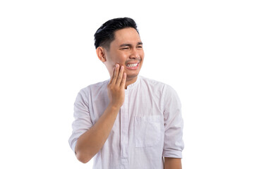 Fototapeta na wymiar Unhealthy Asian Muslim man suffering from acute toothache, touching cheek with painful expression isolated on white background. Ramadan and Eid Fitr celebration concept