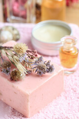 Rose and lavender handmade soap on o pink towel. Other cosmetics in the background.