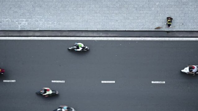 Traffic transportation on road. Drone aerial cityscape top view. Cars and motorcycles are in a hurry, a street cleaner walks along the sidewalk.