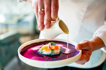 chef cooking Tartar with a scallop on a plate with sauce