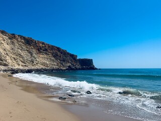 Rocky coast of the ocean bay, clear blue sky, ocean horizon, rocks