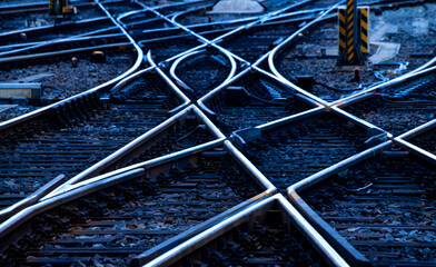 Reflecting symmetrical rails with blue hour twilight. Railway tracks, switches and interchanges at...