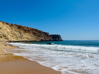 Rocky coast of the ocean bay, clear blue sky, ocean horizon, rocks