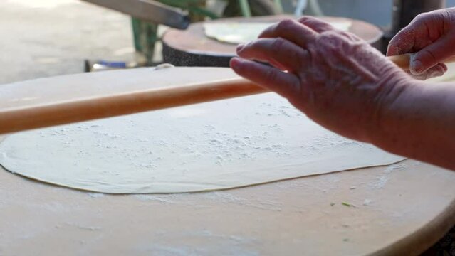 Senior Woman Preparing lavash making with rolling pin.