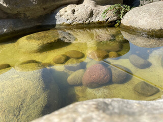 Decorative fish pond with stone ornaments. Ornamental fish swimming in the pond. Sunny day
