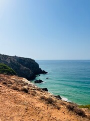 Rocky coast of the ocean bay, clear blue sky, ocean horizon, rocks