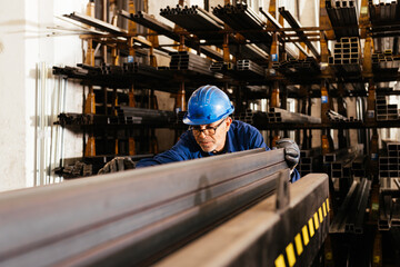 Focused man working pushing steel beam in warehouse
