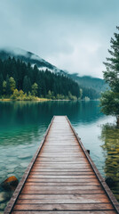 Fototapeta premium wooden bridge path leads to a serene lake, calm water, natural pine tree forest, and misty mountains 