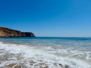 Fototapeta premium Rocky coast of the ocean bay, clear blue sky, ocean horizon, rocks