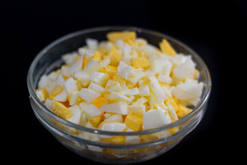 chopped chicken eggs in a cup on a black background