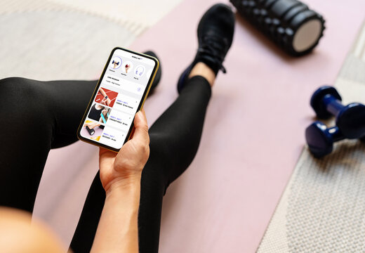 Woman uses a mobile fitness application on her smartphone. Digital online sports assistant.  - Powered by Adobe