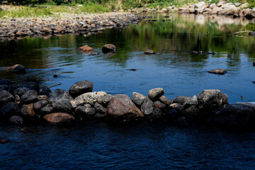 Abstract background stream of water, Waterfall stream on rocks, Rocky riverbank, Calm water stream around the rocks, Stream