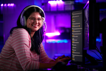 Portrait Of Female Gamer In Front Of Computer Screens With Headphones And Controller